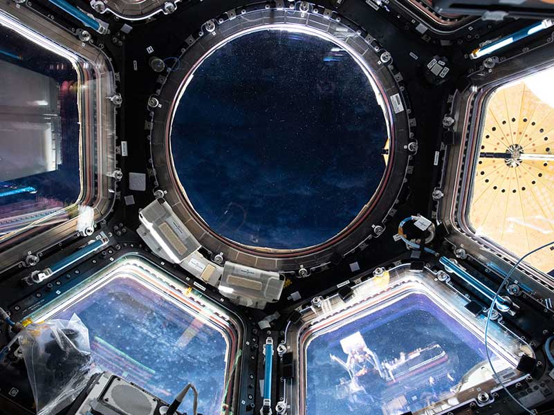 Orbital nighttime peeks through the International Space Station's cupola, or "window to the world," nearly 270 miles above the Indian Ocean. In the right window, the cymbal-shaped solar array that powers Northrop Grumman's Cygnus spacecraft can be seen.