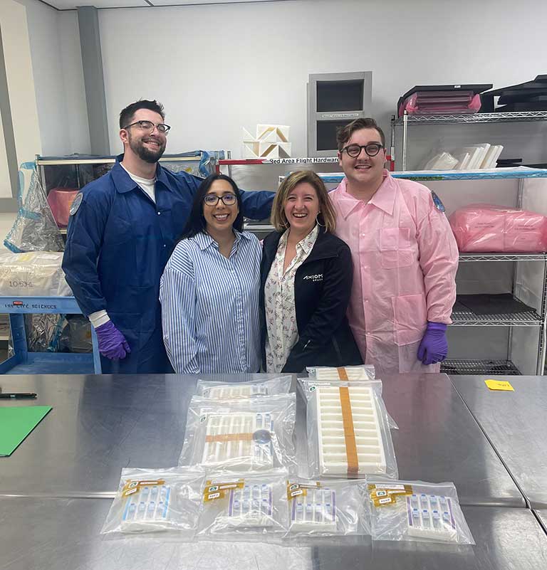 upward-81-janus-ucon-grads-spx30 University of Connecticut graduate students Max Landolina (far left) and Trystin Cote (far right) work with Alexis Rios and Pinar Mesci from Axiom Space to prepare the team's SpaceX CRS-30 investigation.