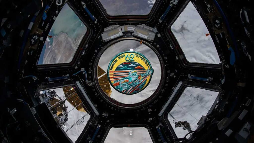 Feb. 21, 2020) — The Expedition 62 mission patch floats inside the seven-window cupola, the International Space Station’s “window to the world.” The orbiting complex was flying 265 miles above Russia near the Caspian Sea at the time this photograph was taken.