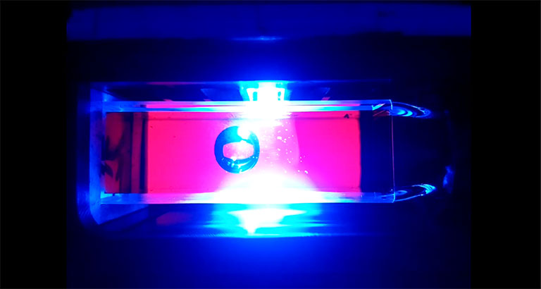 A bubble hovers inside a transparent cuvette as a beam of light strikes the fluid.