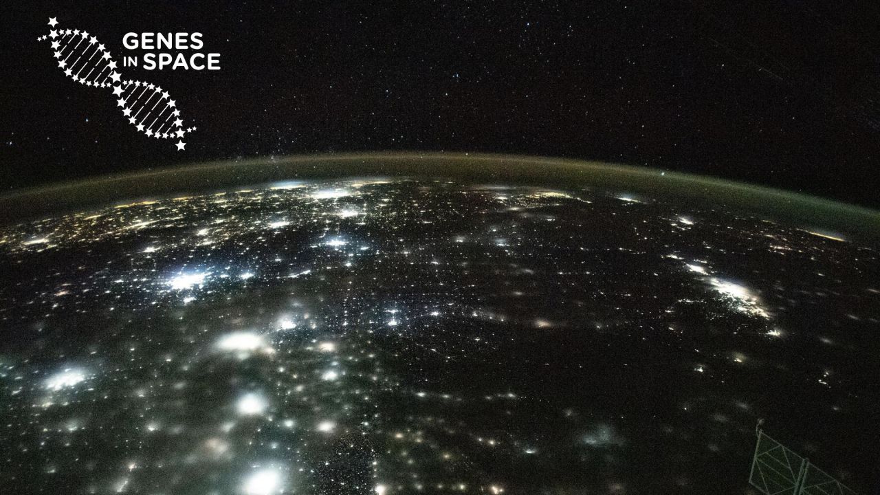 The city lights of North America appear under Earth's airglow and a starry night sky in this photograph from the International Space Station as it orbited 262 miles above Earth. Paired with the Genes in Space logo.